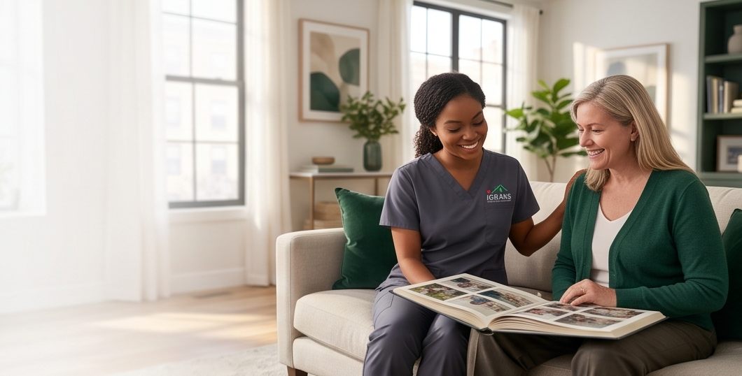 An IHCS caregiver and a client smiling over a photo album together on a sunlit sofa